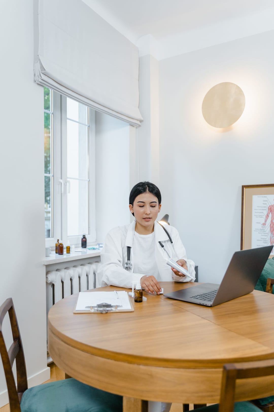 A physician reviewing notes at a laptop in a bright, calm consultation room