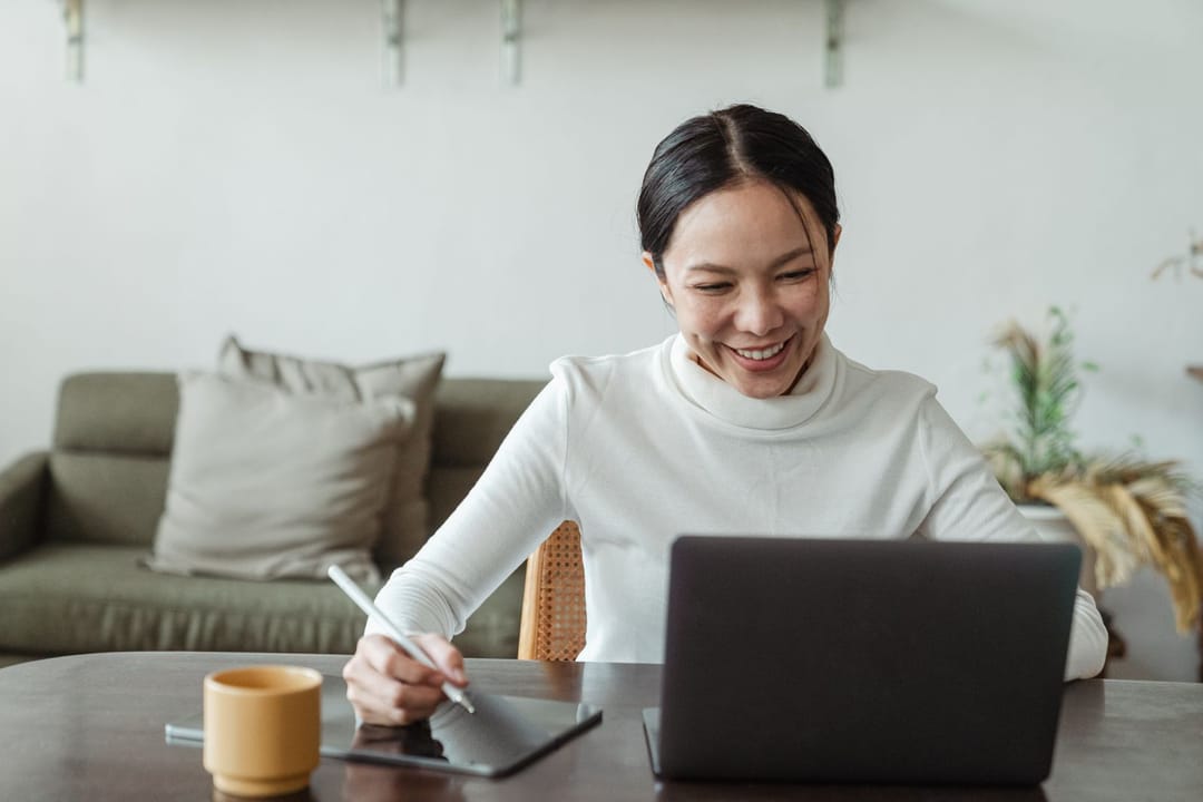 A woman smiling during a video appointment on her laptop at home